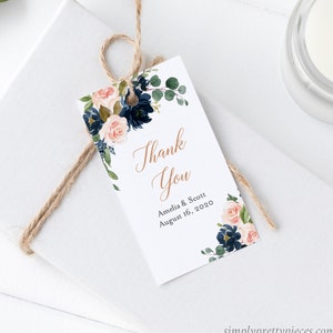 May include: A white thank you tag featuring a floral design in shades of pink, blue, and green. The text "Thank You" is written in cursive script. The tag also includes the text "Amelia & Scott August 16, 2020".