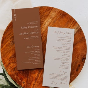 Może przedstawiać: Karta programu ceremonii ślubnej z brązowym tłem i białym tekstem. Karta zawiera listę kolejności wydarzeń ceremonii, w tym preludium, zajmowanie miejsc przez rodziny, procesję, powitanie, czytania, wymianę przysięgi, wymianę obrączek, błogosławieństwo, przedstawienie pary i wyjście. Karta zawiera również nazwiska gości weselnych, w tym officjanta, rodziców panny młodej i pana młodego, druhny, druhen, świadków, drużby, druhnę i druhnę. Karta jest ozdobiona prostym, eleganckim wzorem.