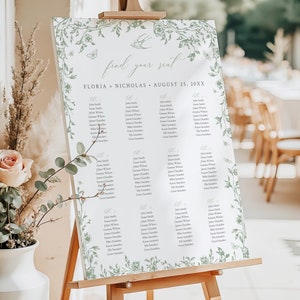 May include: A wedding seating chart with a floral design. The chart is on an easel and has the names of guests listed under different table numbers. The text at the top of the chart reads "find your seat" and "FLORIA + NICHOLAS - AUGUST 25, 20XX".