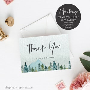 May include: Thank You card with a watercolor illustration of a mountain range and pine trees in shades of blue and green. The text "Thank You" is written in a handwritten font and the names "Helen & Elliot" are printed below.
