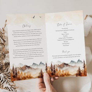 May include: A funeral program with a watercolor illustration of a mountain range with trees in autumn colors. The text on the program includes the order of service, an obituary for Shaun Parkinson, and a thank you message to attendees.