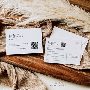 K&ouml;nnte beinhalten: Zwei wei&szlig;e RSVP-Karten mit einem schwarz-wei&szlig;en Design. Die obere Karte hat einen QR-Code und den Text "kindly REPLY BY AUGUST 1ST" und "PLEASE SCAN TO RSVP ON OUR WEDDING WEBSITE. www.OURWEDDINGWEBSITE.COM". Die untere Karte hat einen QR-Code und den Text "kindly REPLY BY AUGUST 1ST" und "Bitte scannen Sie den QR-Code, um zu antworten. Wenn Sie Ihre Antwort per Post senden m&ouml;chten, frankieren Sie sie einfach mit einer Briefmarke und senden Sie sie ab".