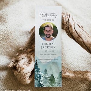 May include: A blue and green watercolor bookmark with a photo of a man and the text "Celebrating the Life of Thomas Jackson 19XX - 20XX Your life was a blessing, your memory a treasure. You are loved beyond words, and missed beyond measure."