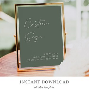 May include: A gold-framed sign with a sage green background. The sign says "Custom Sign" in white cursive writing. Below the text, it says "Create all the signs you need. Your custom text here."