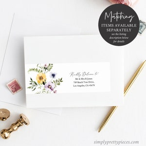 May include: A white envelope with a floral design and a label that reads "Kindly Deliver to Mr & Mrs R Jones 789 Beach Tree Drive, Los Angeles, CA 45678". The envelope is on a white surface with a gold pen and a stamp.
