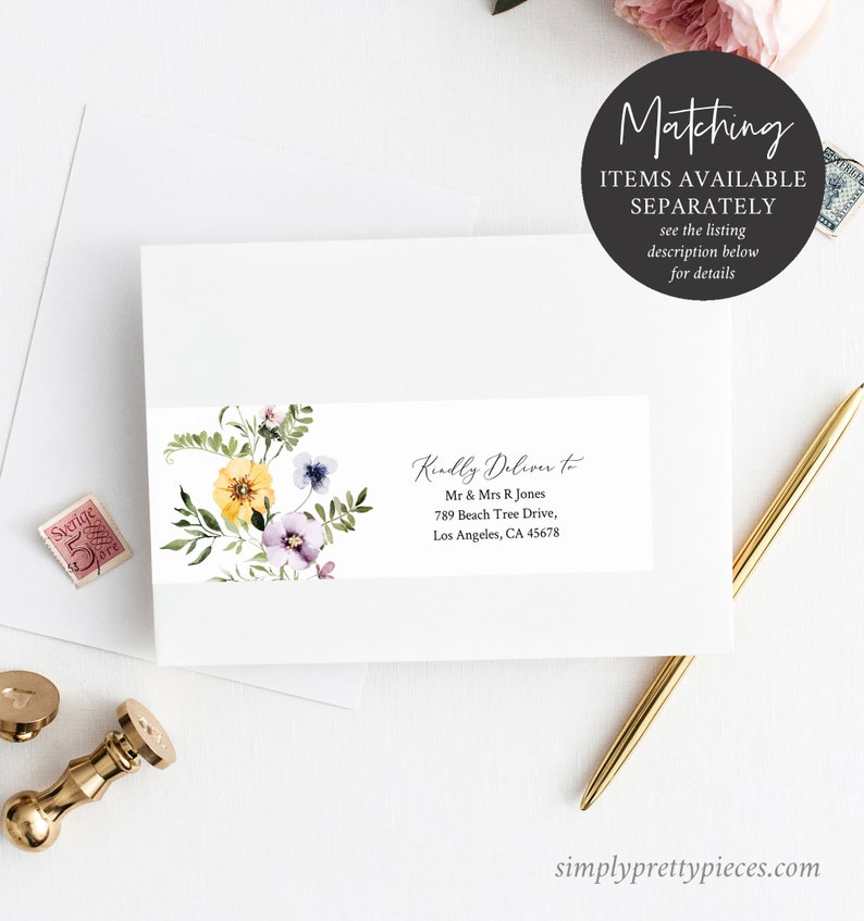 May include: A white envelope with a floral design and a label that reads "Kindly Deliver to Mr & Mrs R Jones 789 Beach Tree Drive, Los Angeles, CA 45678". The envelope is on a white surface with a gold pen and a stamp.
