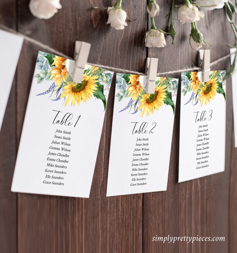 K&ouml;nnte beinhalten: Drei Tischkarten mit Sonnenblumen- und Gr&uuml;npflanzenmotiven. Die Karten sind mit "Tisch 1", "Tisch 2" und "Tisch 3" beschriftet und listen die Namen f&uuml;r jeden Tisch auf.