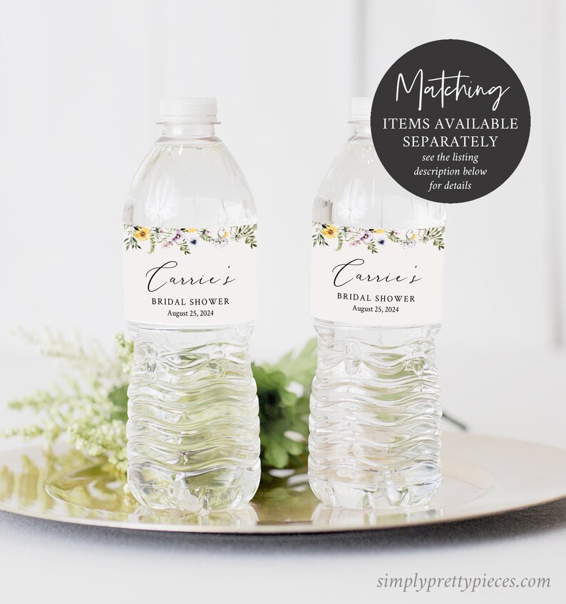 May include: Two clear plastic water bottles with labels that say "Carrie's Bridal Shower August 25, 2024". The labels have a floral design with yellow, purple, and green flowers.