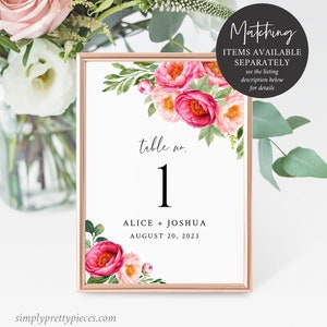 Puede incluir: Una tarjeta de n&uacute;mero de mesa blanca con un dise&ntilde;o floral rosa. La tarjeta tiene un marco dorado y dice "table no. 1" con el texto "ALICE + JOSHUA AUGUST 20, 2023" debajo del n&uacute;mero.