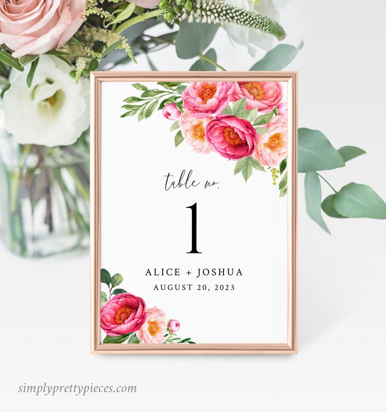 May include: A white table number card with pink floral illustrations. The card has the text "table no. 1" and "Alice + Joshua August 20, 2023".