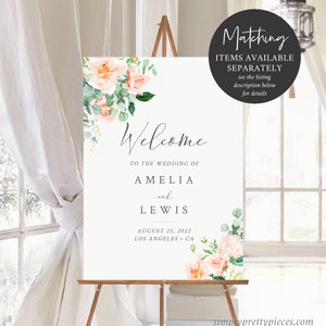Op de afbeelding: Welkom bord met perzik en groene bloemen. Het bord staat "Welkom op de bruiloft van Amelia en Lewis, 25 augustus 2022, Los Angeles, Californi&euml;".