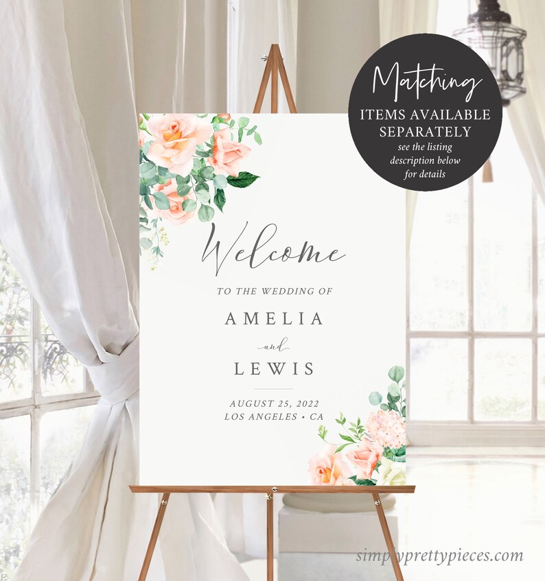 Op de afbeelding: Welkom bord met perzik en groene bloemen. Het bord staat "Welkom op de bruiloft van Amelia en Lewis, 25 augustus 2022, Los Angeles, Californi&euml;".