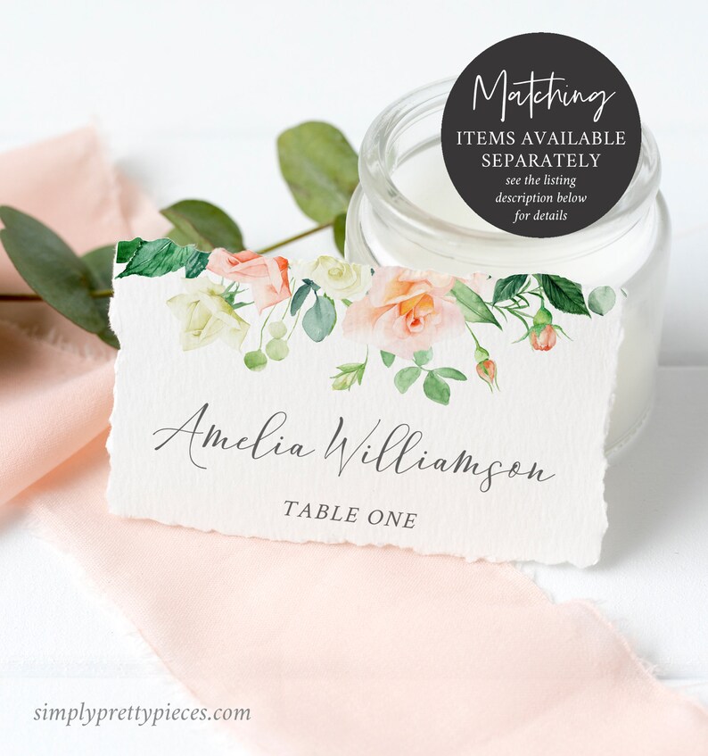 Op de afbeelding: Een wit placecard met een aquarel bloemenontwerp in roze en groene tinten. De tekst "Amelia Williamson" en "Tafel E&eacute;n" is in grijs op de kaart gedrukt.