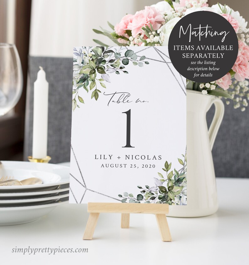 Puede incluir: Tarjeta de mesa de boda n&uacute;mero uno con un dise&ntilde;o floral verde y blanco y un patr&oacute;n geom&eacute;trico plateado. La tarjeta dice "Table no. 1" y "Lily + Nicolas August 25, 2020".