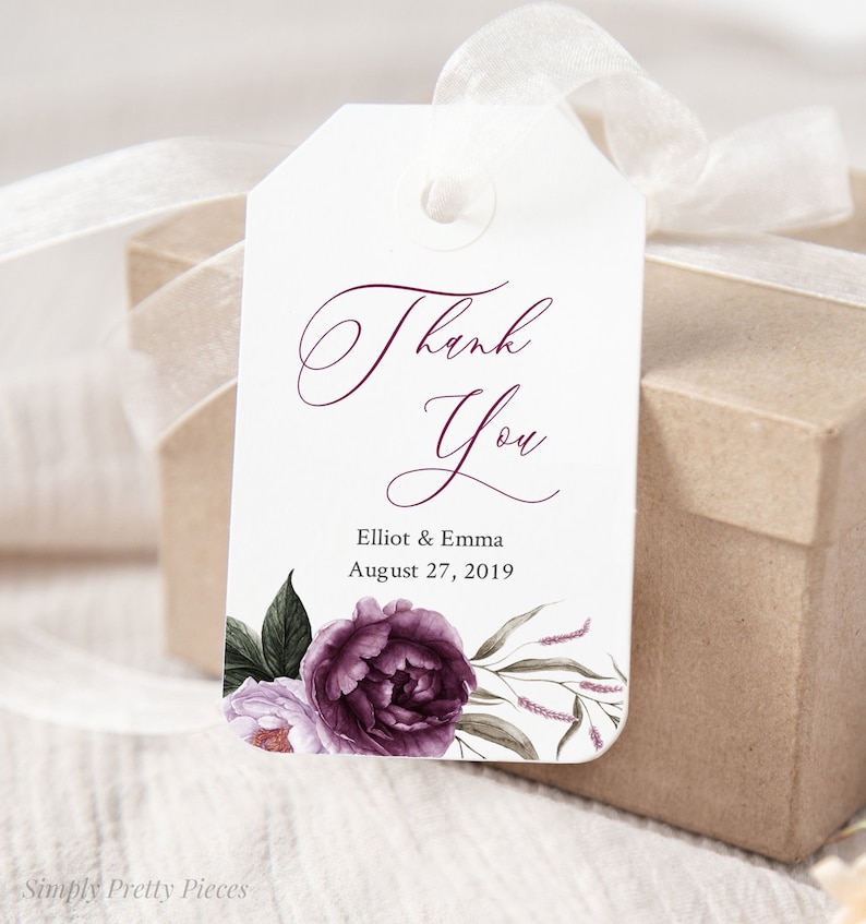 May include: White thank you tag with a purple floral design. The text reads "Thank You" in a script font. Below the text is "Elliot & Emma" and "August 27, 2019".