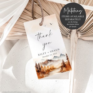 May include: A thank you tag with a watercolor illustration of a mountain range, trees, and a river. The text reads "thank you" with the names Riley and Shaun and the date October 15, 2022.