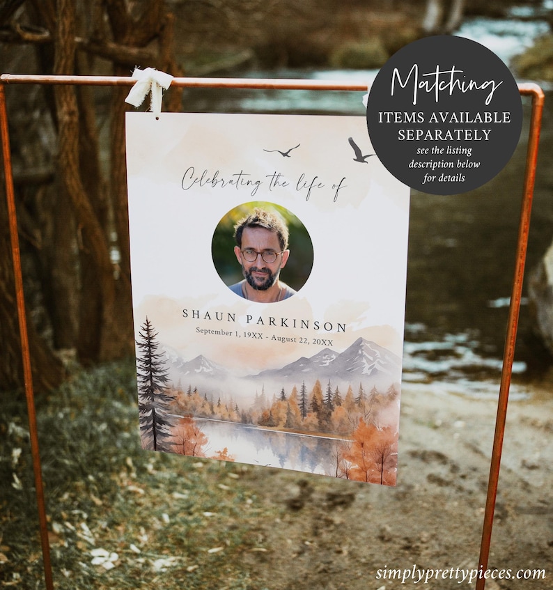 May include: A memorial sign with a watercolor background of a lake and mountains in fall colors. The sign says "Celebrating the life of Shaun Parkinson" with dates of birth and death. A photo of Shaun is in a circle at the top of the sign.
