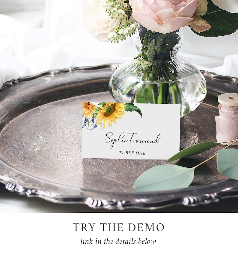 May include: A white place card with a sunflower and floral design. The text on the card reads "Sophie Townsend, Table One".