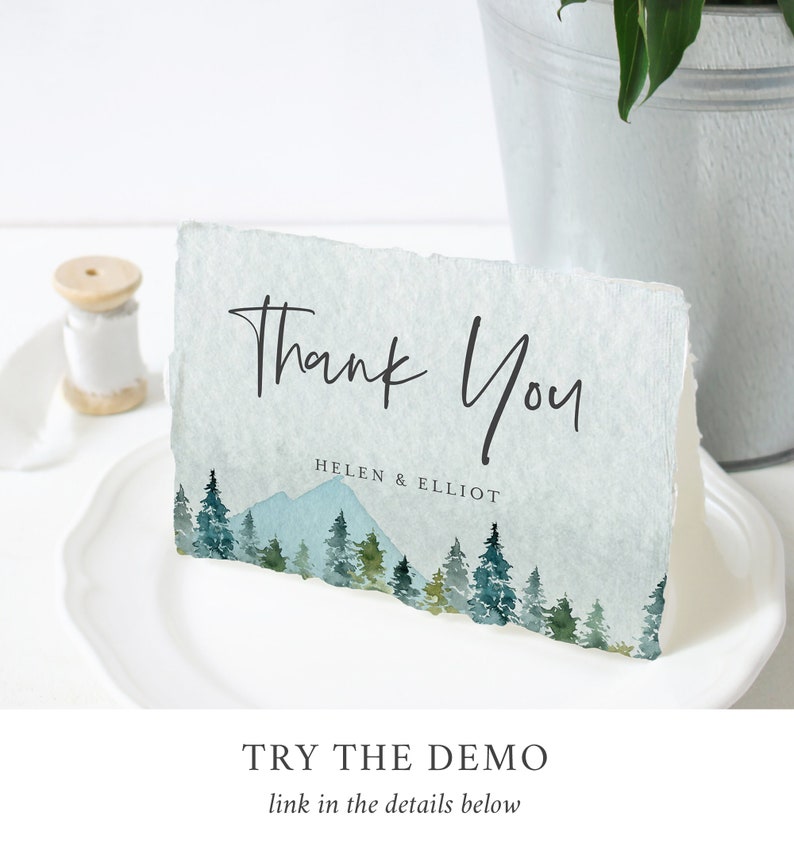 Puede incluir: Una tarjeta de agradecimiento con una ilustraci&oacute;n de acuarela de una cordillera y pinos. El texto "Gracias" est&aacute; escrito en letra cursiva negra y los nombres "Helen & Elliot" est&aacute;n impresos debajo.