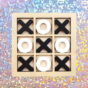 Könnte beinhalten: Holz-Tic-Tac-Toe-Spiel mit schwarzen X's und weißen O's. Das Spielbrett ist ein hellbraunes Quadrat mit einem Raster von neun Feldern. Die X's sind tiefschwarz und die O's sind weiße Kreise. Der Hintergrund ist eine schimmernde, irisierende Oberfläche.