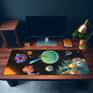 Pode incluir: Um tapete de mesa retangular preto com uma ilustração colorida com tema espacial. O design inclui planetas, naves espaciais e um planeta verde vibrante com um raio de energia azul. O tapete está colocado numa secretária de madeira.