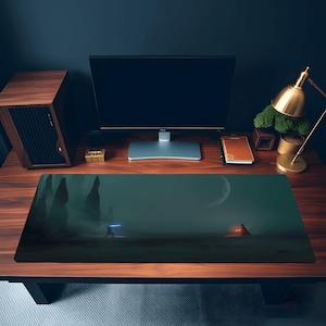 Könnte beinhalten: Rechteckige Schreibtischunterlage mit einer digitalen Kunstszene, die eine Figur mit einem blauen Lichtschwert in einer dunklen, nebligen Landschaft mit einem großen Mond zeigt. Die Unterlage liegt auf einem Holzschreibtisch mit einem Computermonitor.