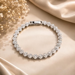 Peut inclure: Un bracelet tennis argenté composé d'une rangée continue de pierres rondes, transparentes et facettées, serties dans une monture métallique. Le bracelet présente un fermoir rectangulaire à cliquet sur le dessus, formant un cercle.
