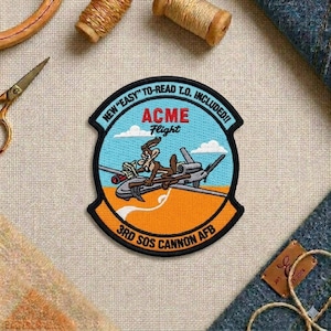 May include: Embroidered patch featuring the ACME Flight logo with a cartoon coyote riding a plane. The patch has a black border and includes the text "NEW 'EASY' TO-READ T.O. INCLUDED!!" and "3RD SOS CANNON AFB".