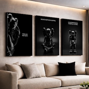 Op de afbeelding: Een set van drie zwart omlijste kunstprints met glanzende zwarte sculpturen met X-vormige ogen. De prints tonen de zinnen "I think more than I speak", "Silence keeps me in control" en "A calm mind creates powerful futures".