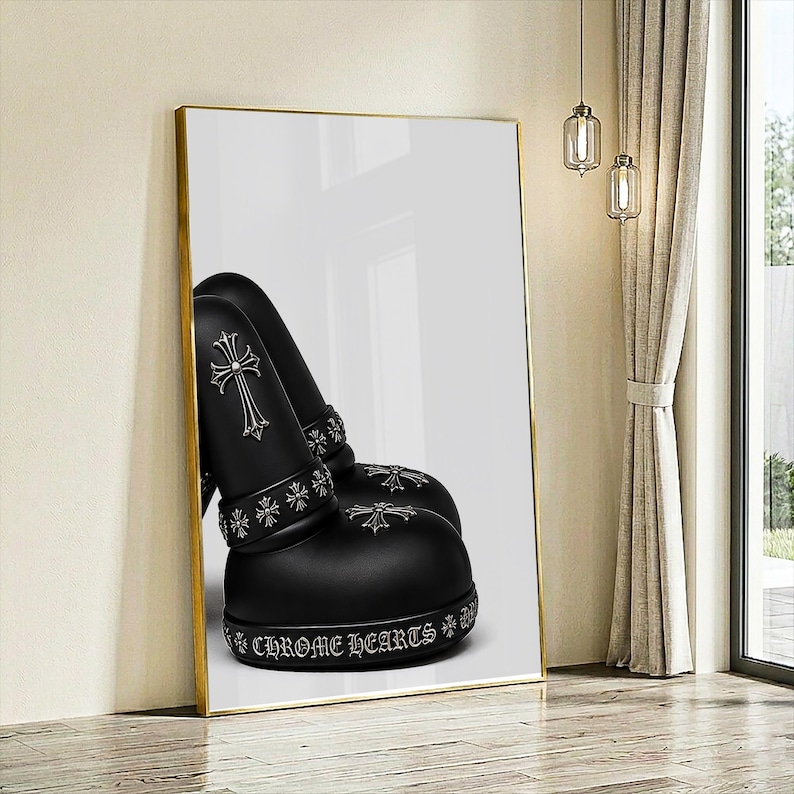 May include: A framed wall art print featuring a pair of matte black boots with silver-toned cross emblems. The boots are adorned with a band of small cross motifs and the text CHROME HEARTS printed in a gothic font along the thick rubber sole.