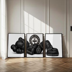May include: Three framed wall art prints featuring black and white imagery. The left print shows a black character figure, the center print displays a Chrome Hearts logo with boxing gloves, and the right print depicts a black shoe with cross motifs.