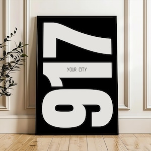 May include: A rectangular wall art print featuring a black background with large, bold white numbers 917 displayed vertically. The text YOUR CITY is printed in a smaller, clean sans-serif font horizontally across the center of the number 1.