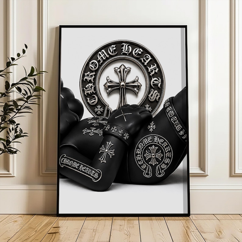 May include: A framed wall art print featuring a black figure adorned with silver Chrome Hearts branding and cross motifs. The design includes a prominent circular emblem with the text Chrome Hearts and a central cross, set against a white background.