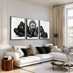 May include: Three framed wall art prints featuring black and white imagery. The left print shows a stylized character figure, the center print displays Chrome Hearts branding with a cross emblem, and the right print depicts black boxing gloves.