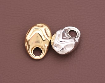 May include: Two small, irregular, organic-shaped metal charms, one with a polished gold-tone finish and the other with a polished silver-tone finish. Each charm features a smooth, undulating surface and a single circular hole at one end.