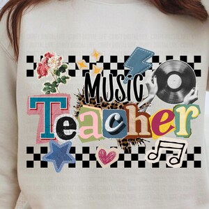 Op de afbeelding: Beige sweatshirt met een collage-ontwerp met de tekst "Music Teacher". Het ontwerp bevat een vinylplaat, muzieknoten, een bliksemschicht, een ster, een hart en bloemen, alles tegen een zwart-wit geblokt patroon.