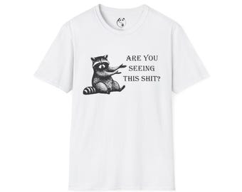 Camiseta con ilustración de un mapache señalando / Texto "¿Estás viendo esta mierda?"