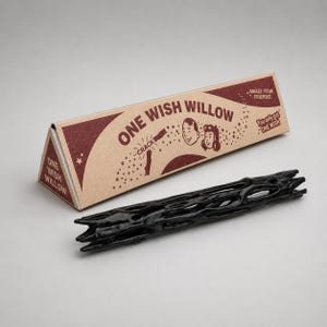 Może przedstawiać: Czarny, porowaty, cylindryczny przedmiot przypominający gałązkę, któremu towarzyszy trójkątne kartonowe pudełko z napisem ONE WISH WILLOW. Pudełko zawiera brązowy tekst, ilustracje dwóch twarzy, gwiazdki oraz frazy AMAZE YOUR FRIENDS i YOU ONLY GET ONE WISH.