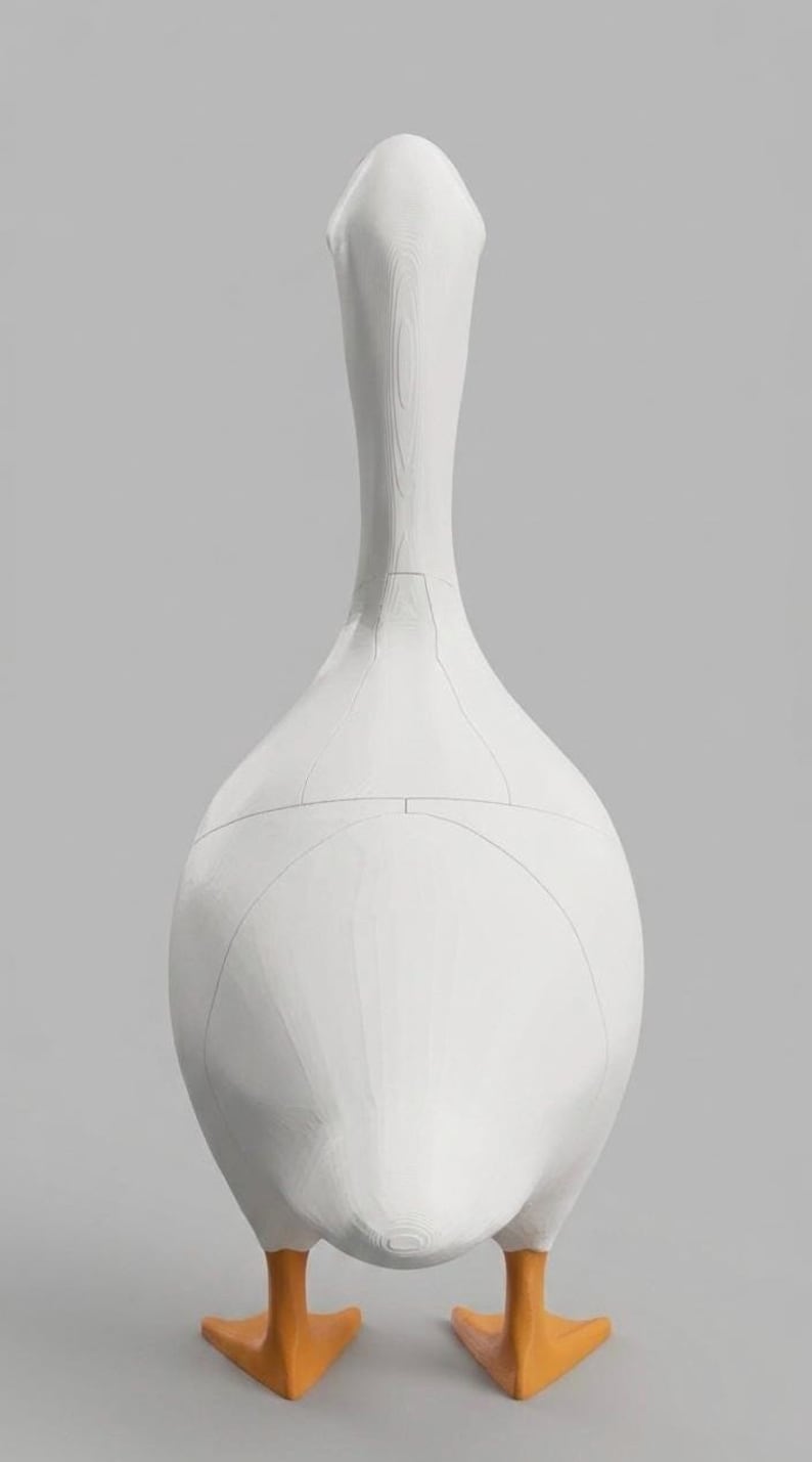 May include: A white goose sculpture with orange feet. The sculpture has a long neck and a rounded body. The design includes visible seam lines. The background is a solid gray.