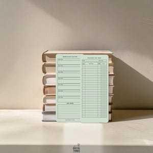May include: A light green reading log and quote journal are displayed in front of a stack of books. The reading log has spaces for title, author, and rating. The quote journal has spaces for memorable quotes and notes.
