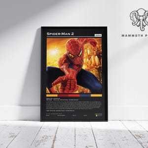 May include: A framed poster for the movie Spider-Man 2, featuring the superhero in his red and blue suit against a cityscape backdrop. The poster includes the movie title, year, and credits.