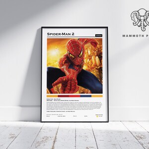May include: A framed poster for the movie Spider-Man 2, featuring the superhero in a red and blue suit. The poster includes the film's title, year, and credits. The background is a cityscape.