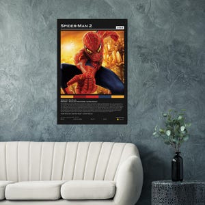 May include: A framed poster of the movie Spider-Man 2, featuring the superhero in a red and blue suit against a cityscape backdrop. The poster includes the movie title, year 2004, and credits.
