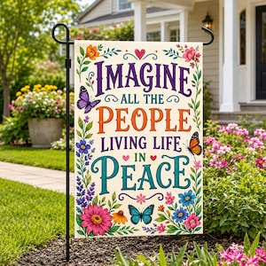 Puede incluir: Una bandera de jardín rectangular con el texto Imagine all the people living life in peace en letras moradas, naranjas y verde azulado. El diseño está rodeado por ilustraciones coloridas de varias flores, hojas verdes y tres mariposas.