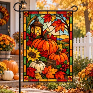 Puede incluir: Una bandera de jardín rectangular con un diseño estilo vitral que muestra tres calabazas, un girasol, bayas rojas y hojas de otoño. Un farol se sitúa detrás de las calabazas, todo enmarcado por un borde decorativo con detalles de hojas.