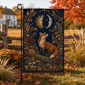 Puede incluir: Una bandera de jardín rectangular con fondo azul oscuro que muestra un zorro naranja sobre un tronco. El diseño incluye un sol y una luna creciente, un cuervo, setas, un erizo y follaje otoñal con hojas de roble y bayas decorativas.
