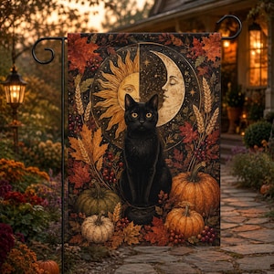 May include: A rectangular garden flag featuring a black cat sitting centrally. Behind the cat is a circular sun and moon motif. The design includes orange and green pumpkins, autumn maple leaves, wheat stalks, and red berries on a dark background.