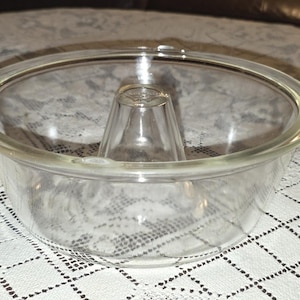 Peut inclure: Un moule à couronne en verre transparent doté d'un bord circulaire lisse et d'une indentation centrale en forme de cône. Cet ustensile de cuisson transparent présente une conception à large bassin ouvert pour une cuisson uniforme.