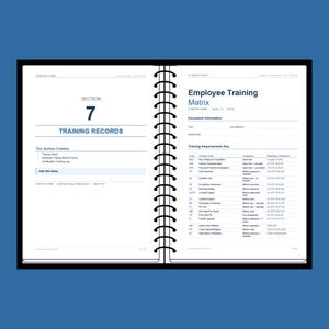 May include: Open notebook with a black cover and spiral binding. The pages display the title "Employee Training Matrix" and "Training Records." The document includes a training requirements key and other training information.