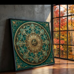 May include: A framed, ornate artwork with a teal and gold circular design. The artwork features intricate patterns and Arabic calligraphy in the center. The frame is black, and the artwork is displayed on a wooden floor near a window with a view of fall foliage.